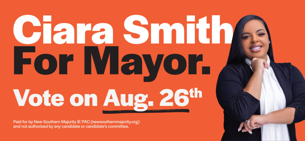 Political billboard featuring portrait of person posed with hands under chin and elbow over a vibrant background.